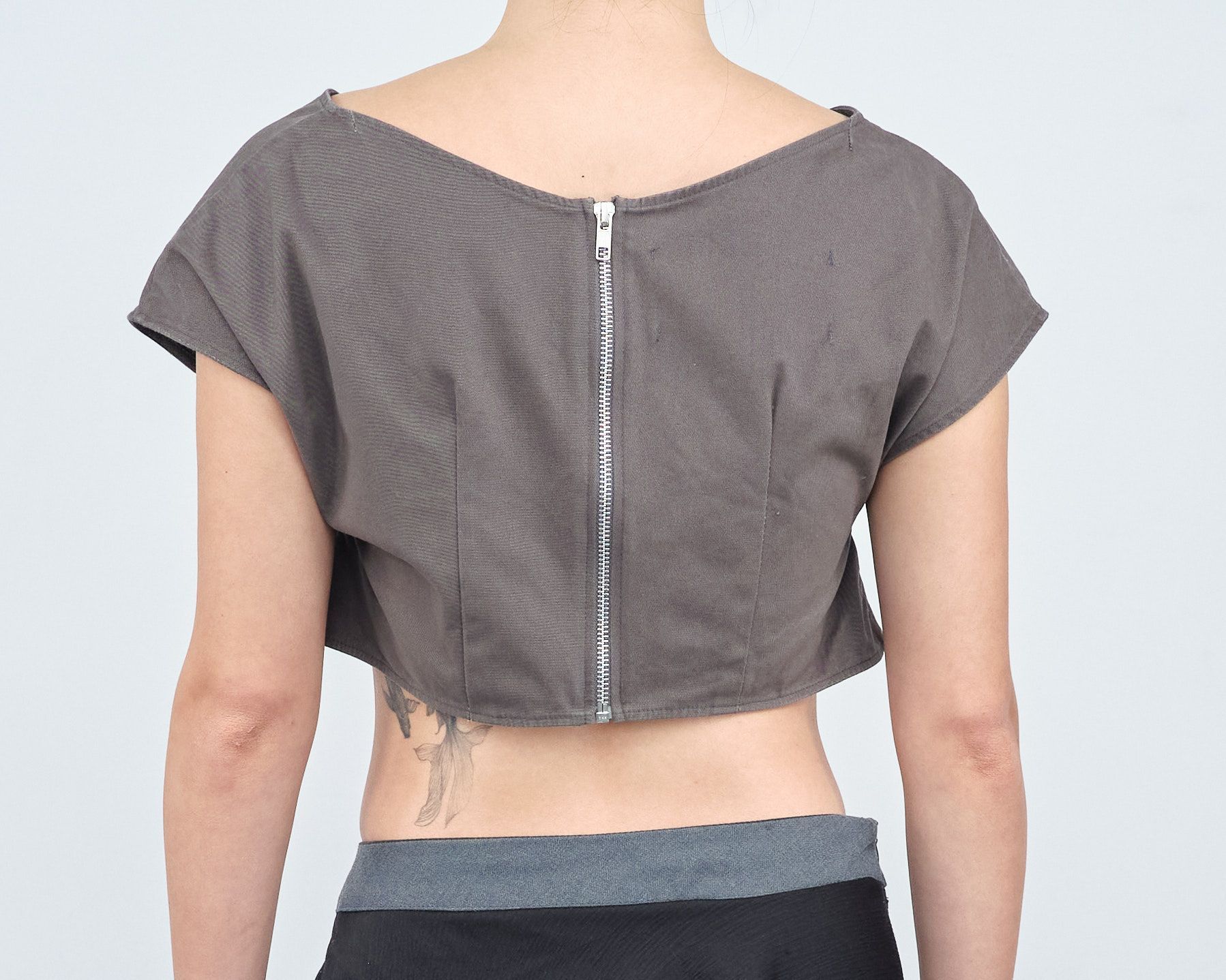 A woman with a tattoo on her back is wearing a crop top