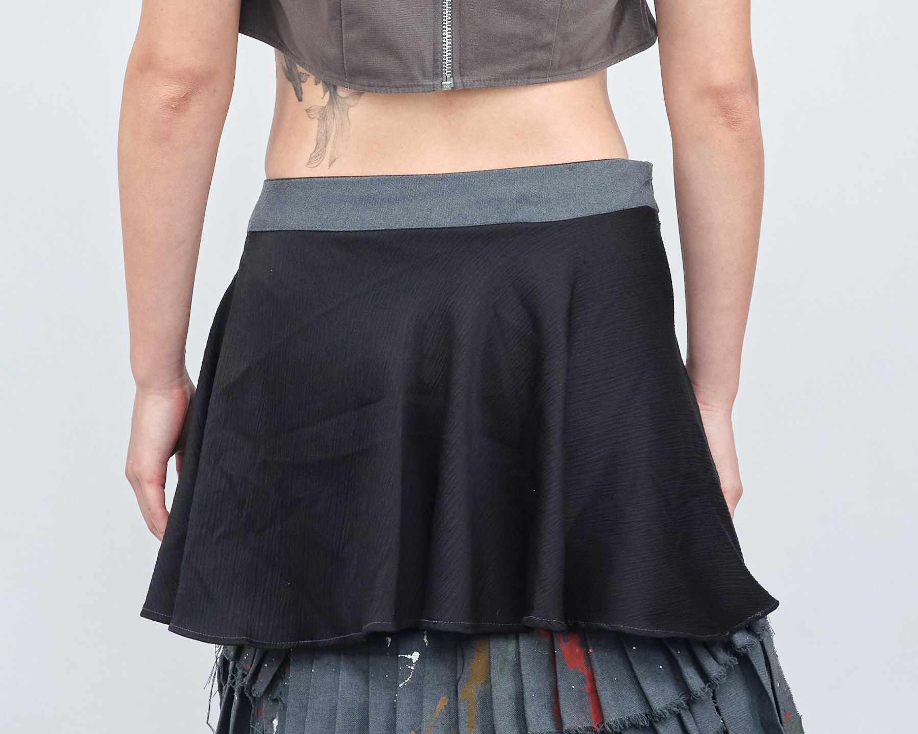 A woman with a tattoo on her back is wearing a black skirt