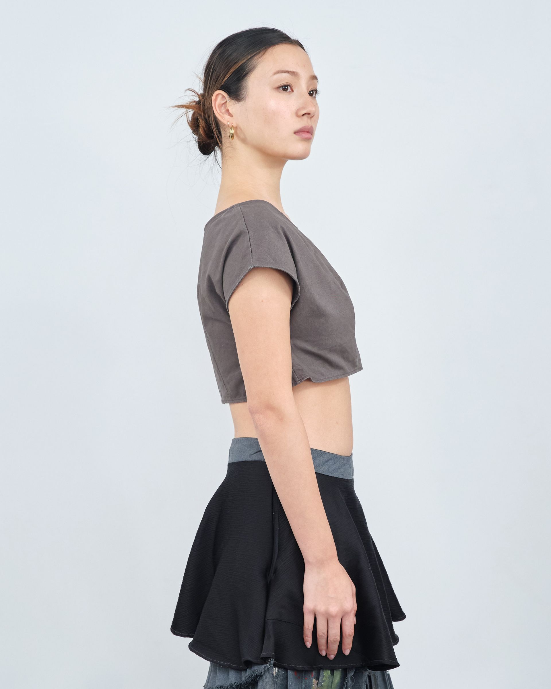 A woman is wearing a crop top and a black skirt.