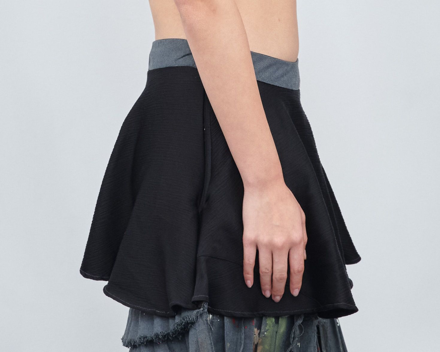 A woman is wearing a black skirt and a crop top