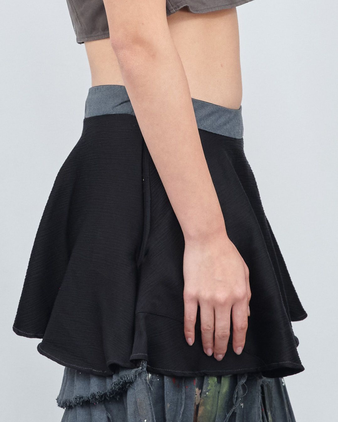 A woman is wearing a black skirt and a crop top