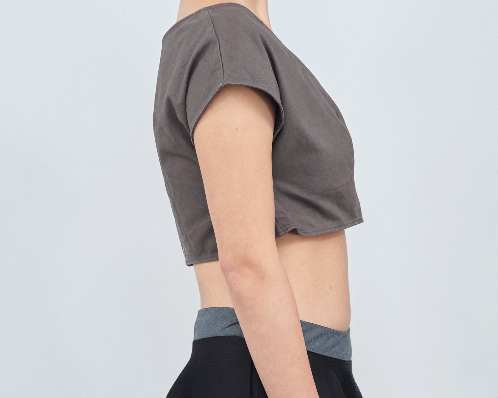 A woman is wearing a crop top and black skirt.