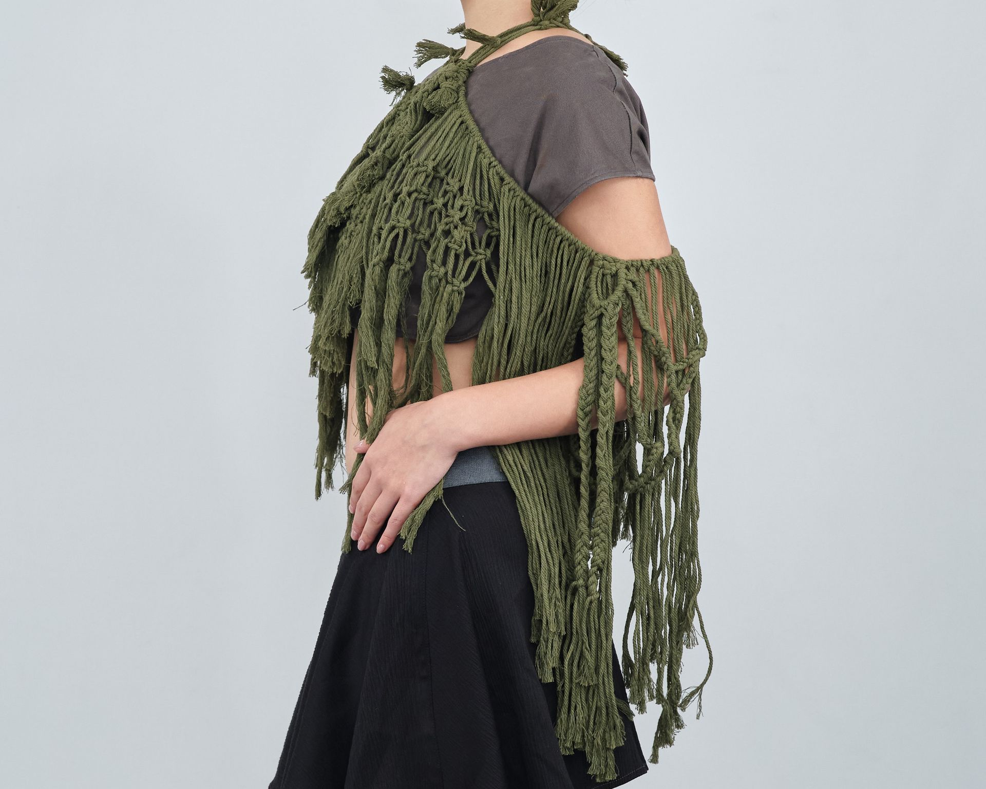 A woman wearing a green vest with fringe and a black skirt