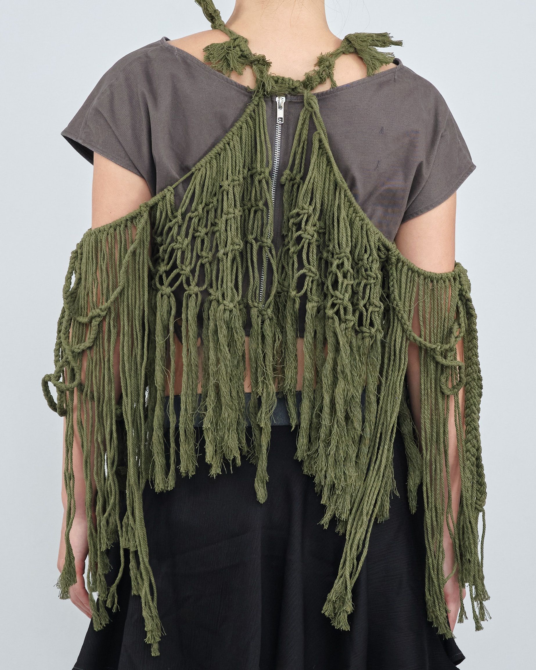 A woman wearing a green fringed top and black skirt