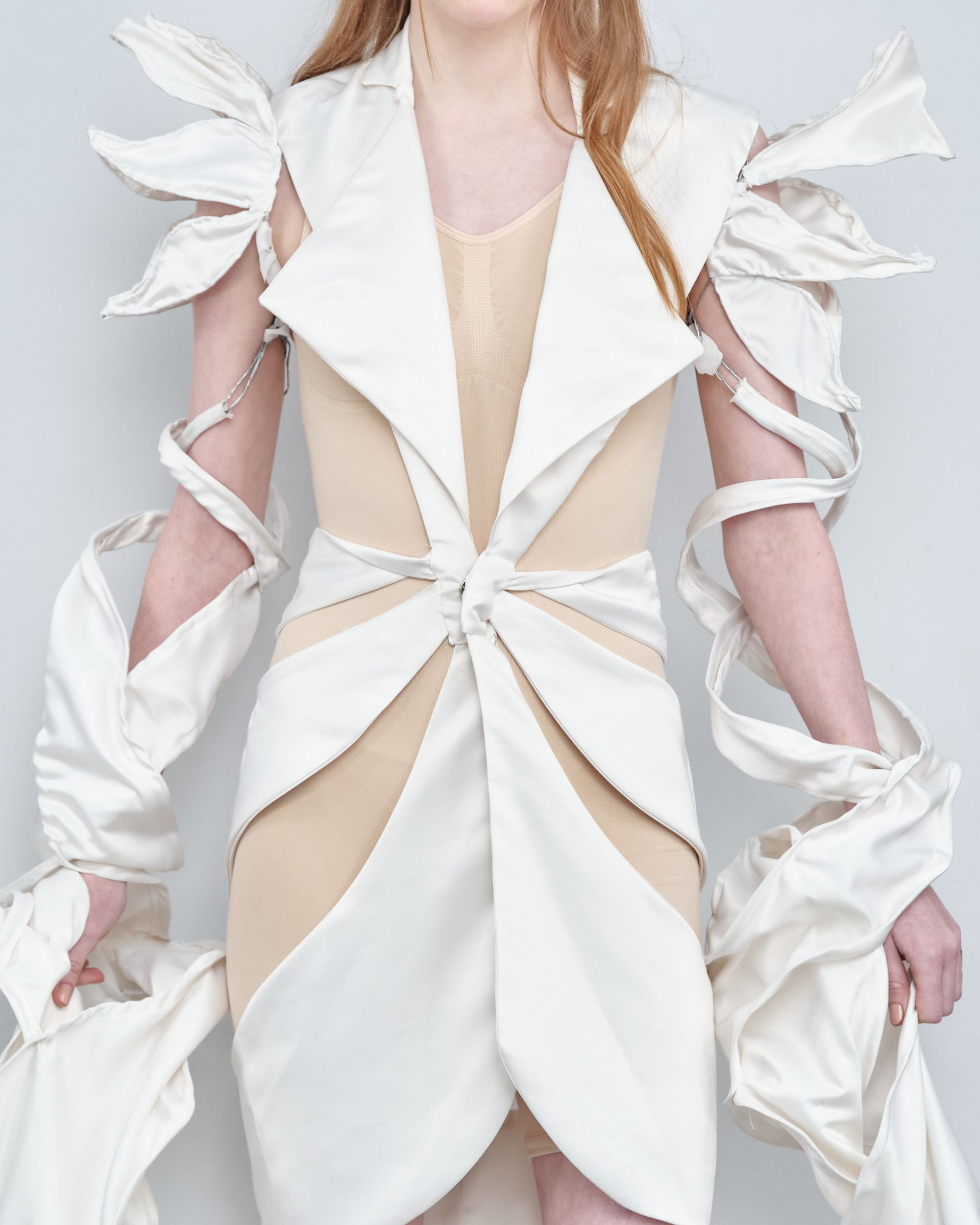 A woman wearing a white dress with ribbons around her arms