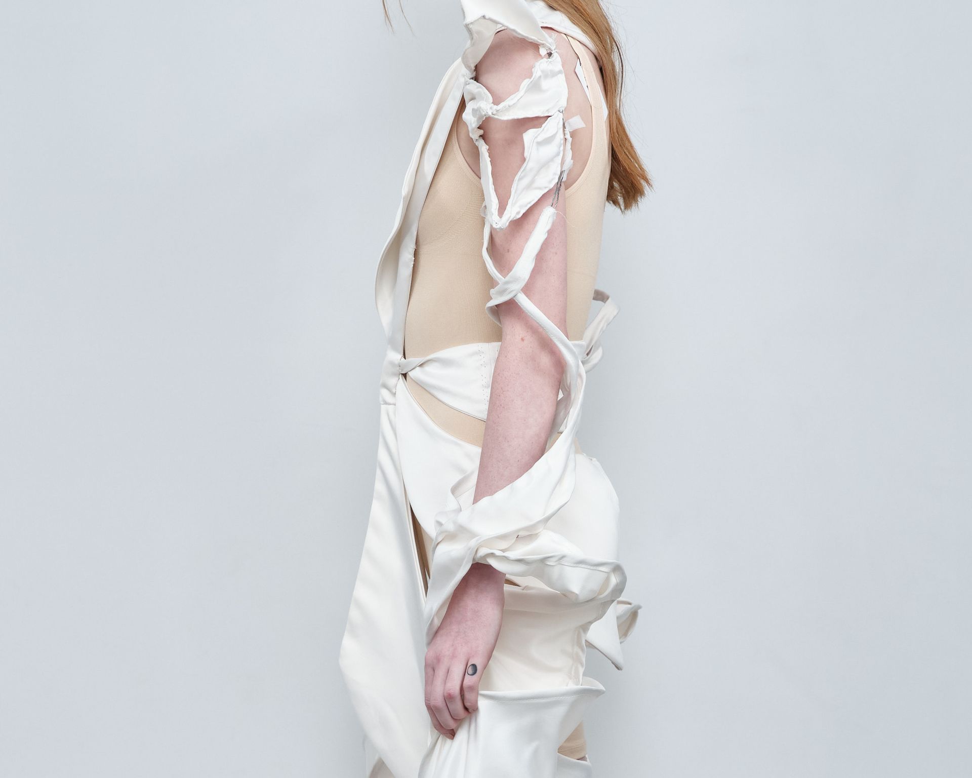 A woman wearing a white dress with ribbons around her arms