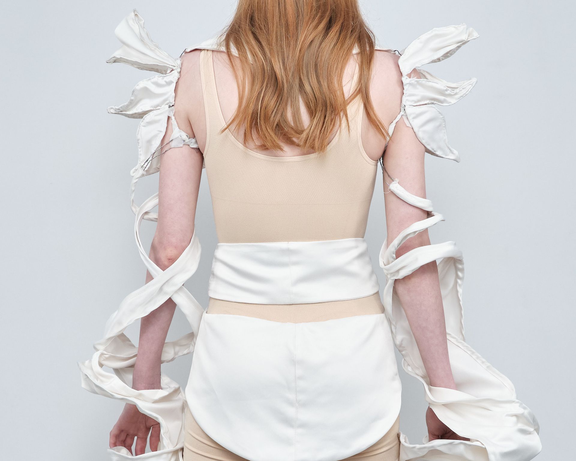 The back of a woman wearing a tan tank top and white shorts