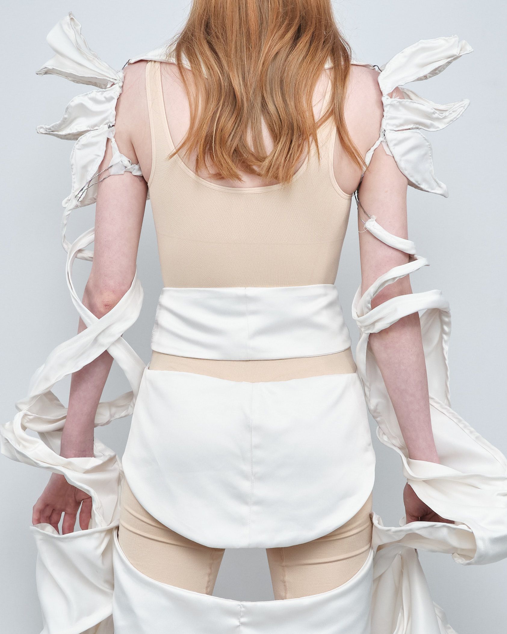 The back of a woman wearing a tan top and white pants