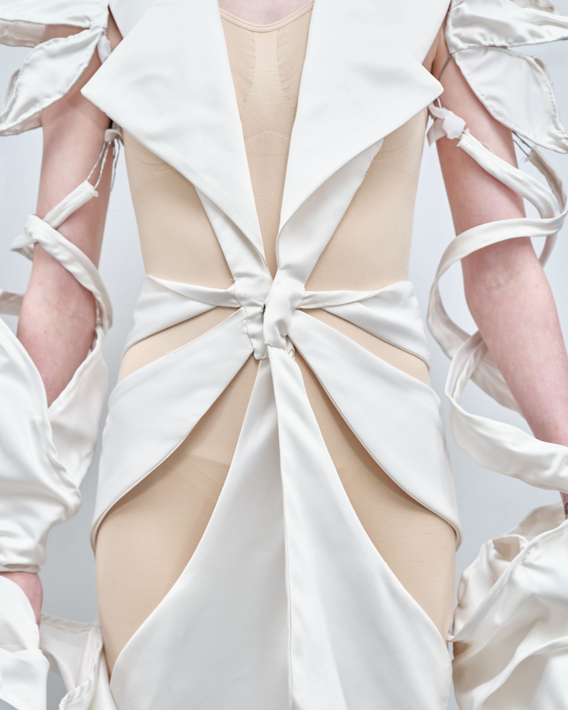 A woman is wearing a white dress with ribbons around her arms