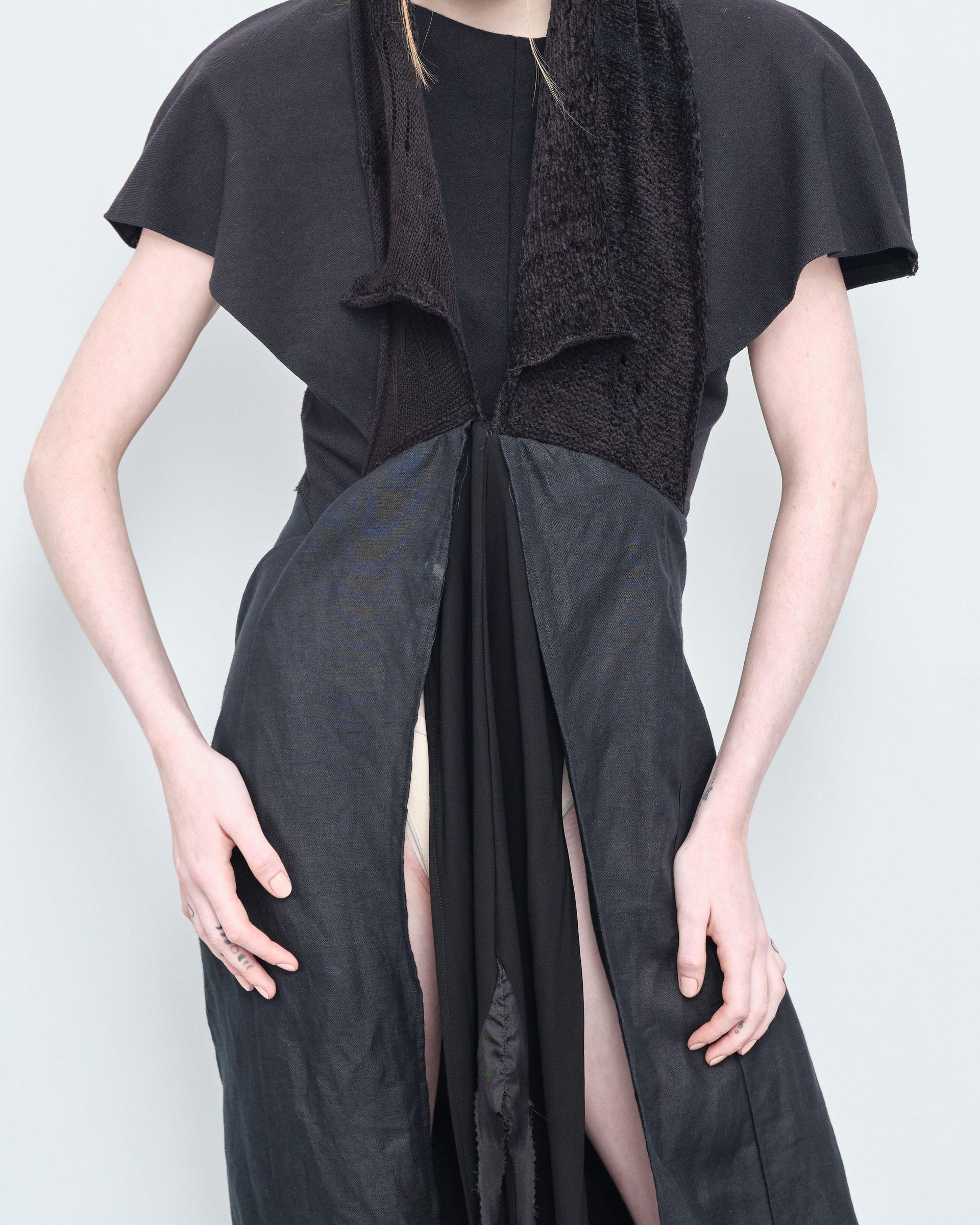 A woman is wearing a black dress with a high slit