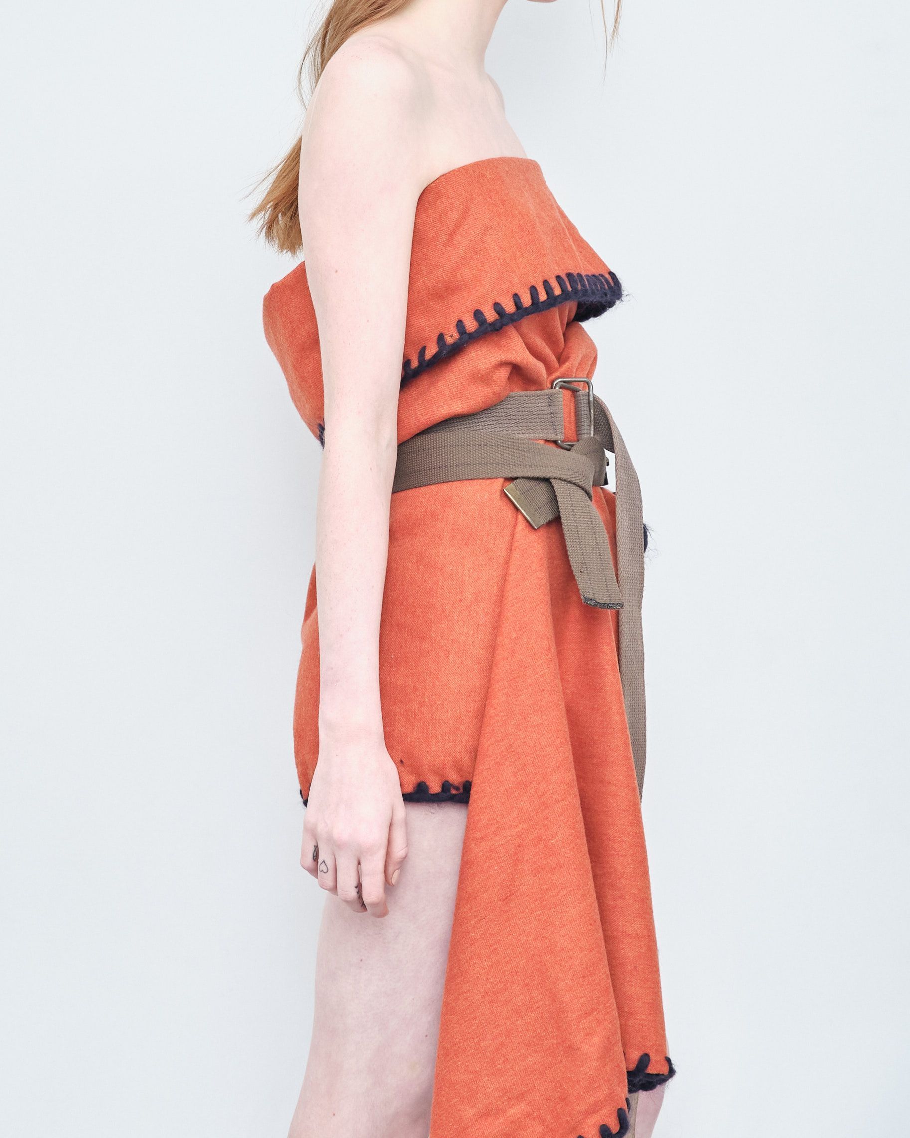 A woman is wrapped in an orange towel and has a belt around her waist