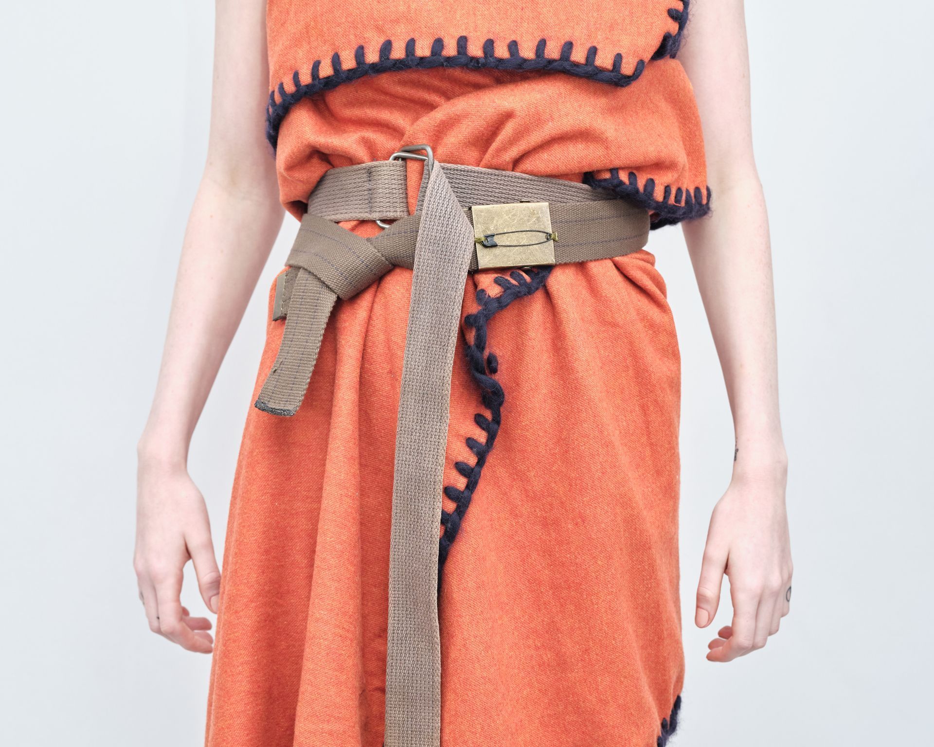 A woman wearing an orange towel dress with a belt around her waist