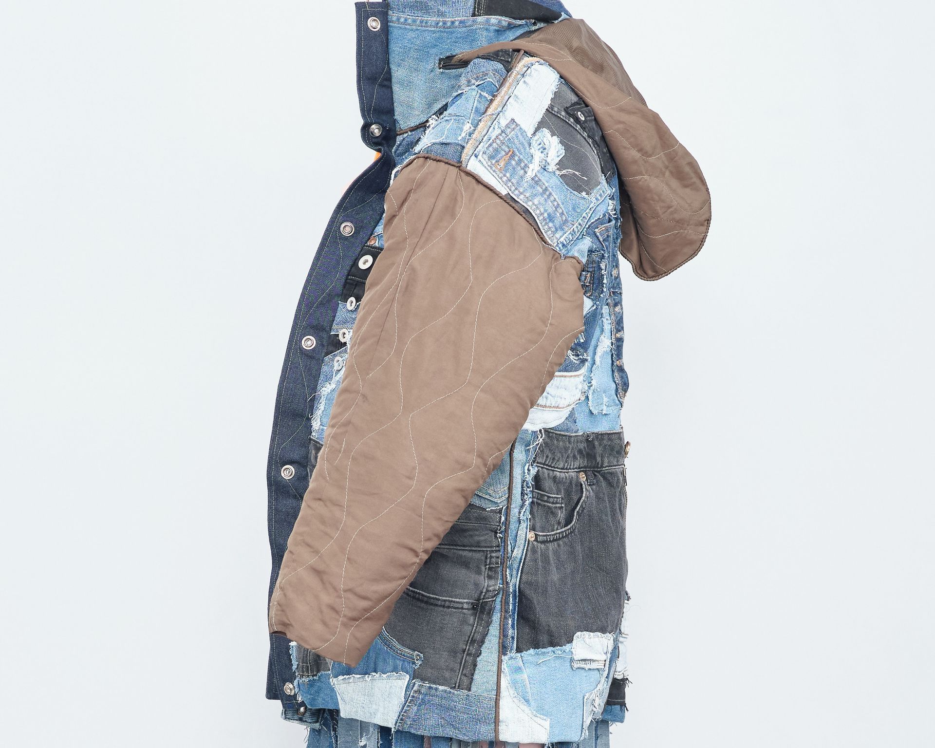 A person is wearing a denim jacket with a hood and brown sleeves.
