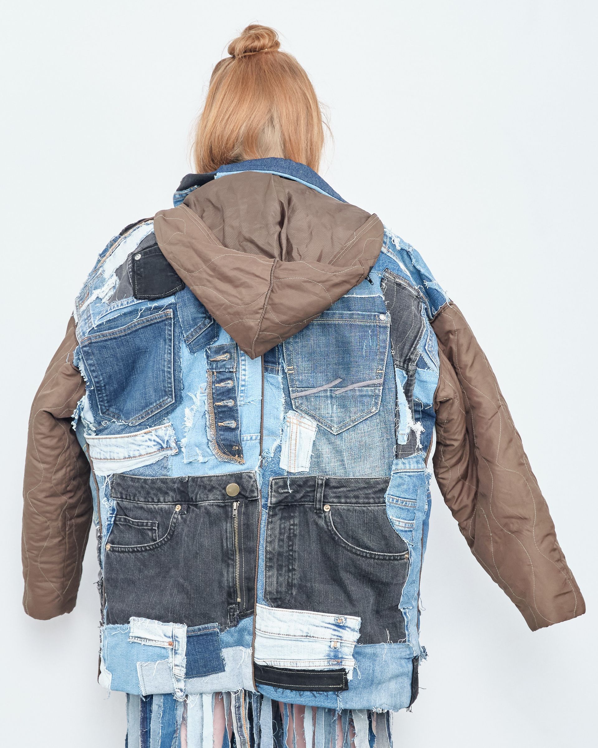 A woman is wearing a patchwork denim jacket with a hood.