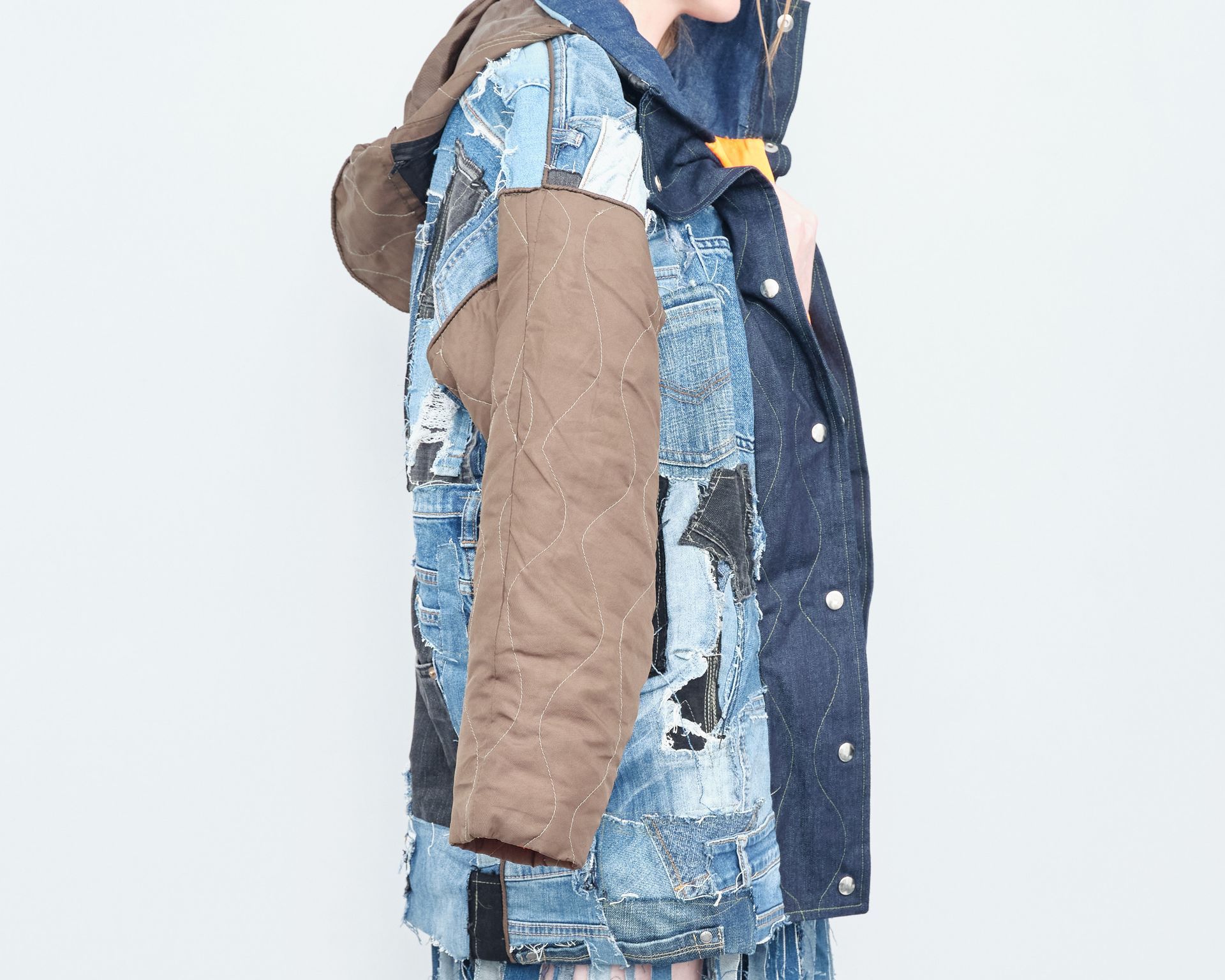 A woman is wearing a patchwork jacket with a hood.