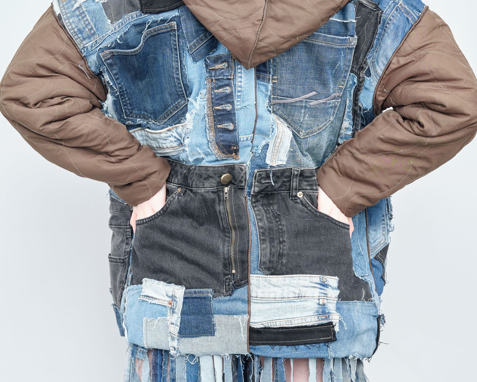 A person wearing a patchwork denim jacket with brown sleeves