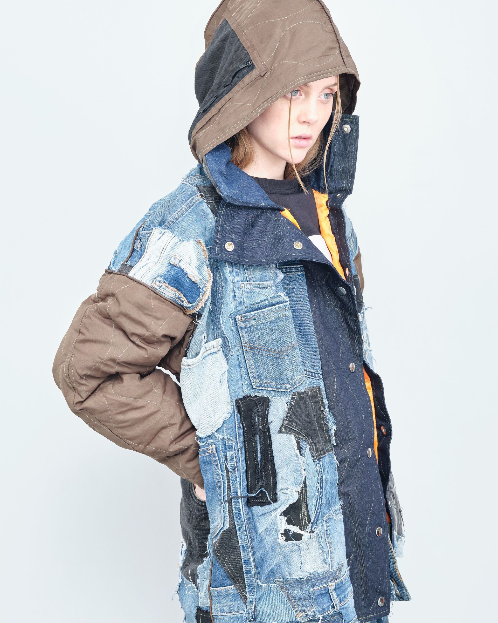 A woman is wearing a patchwork jacket with a hood.