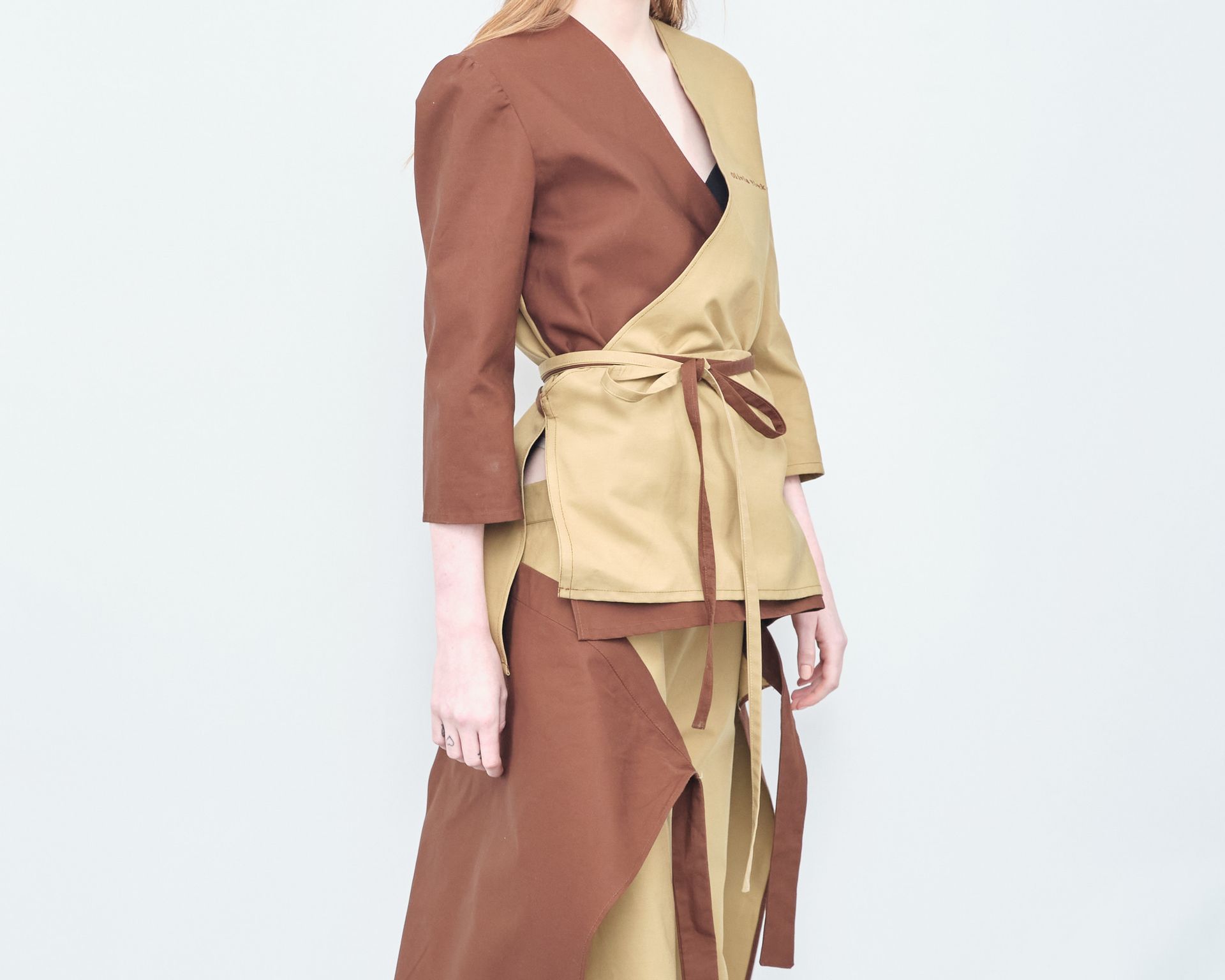 A woman is wearing a brown jacket and a tan skirt.