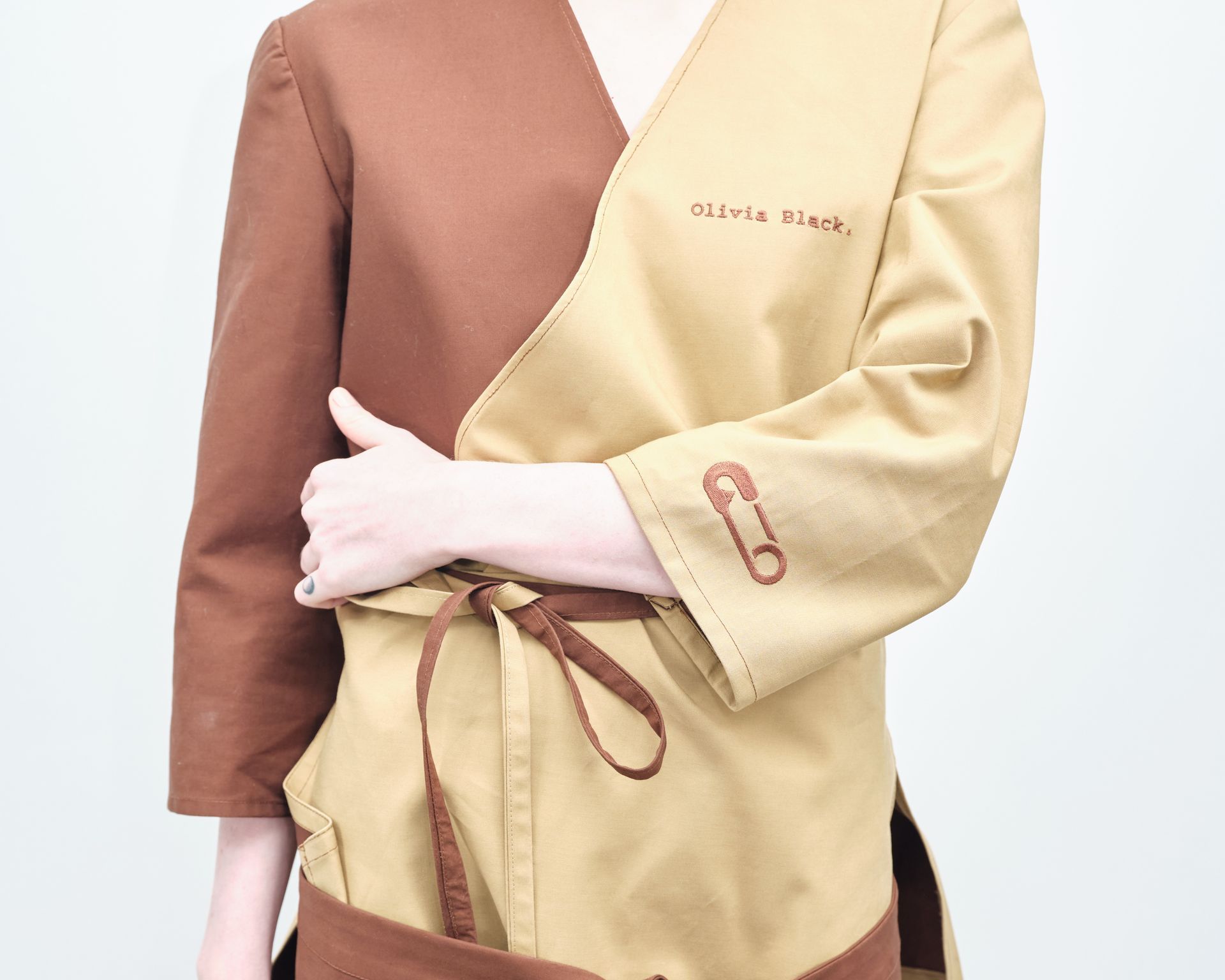 A woman is wearing a brown and tan dress with a belt around her waist