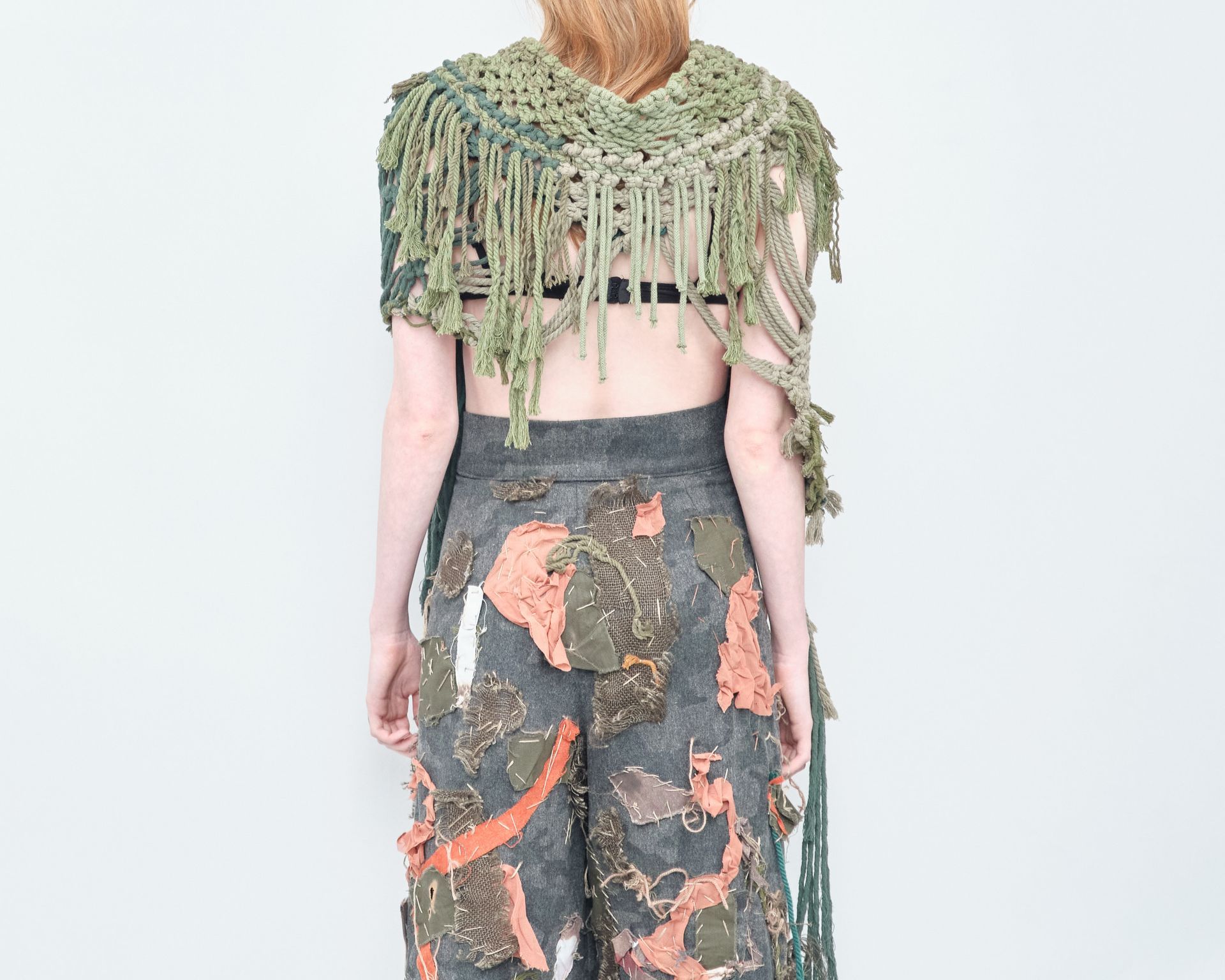 The back of a woman wearing a scarf and pants.