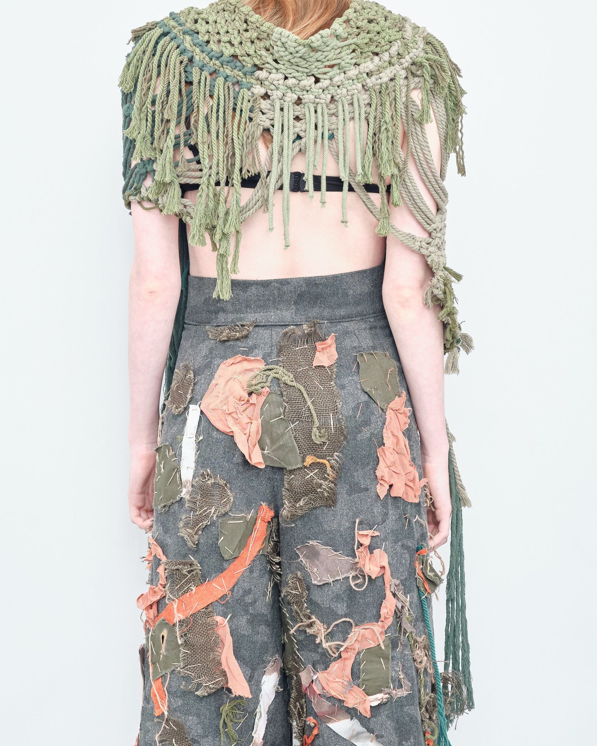 The back of a woman wearing a scarf and pants.