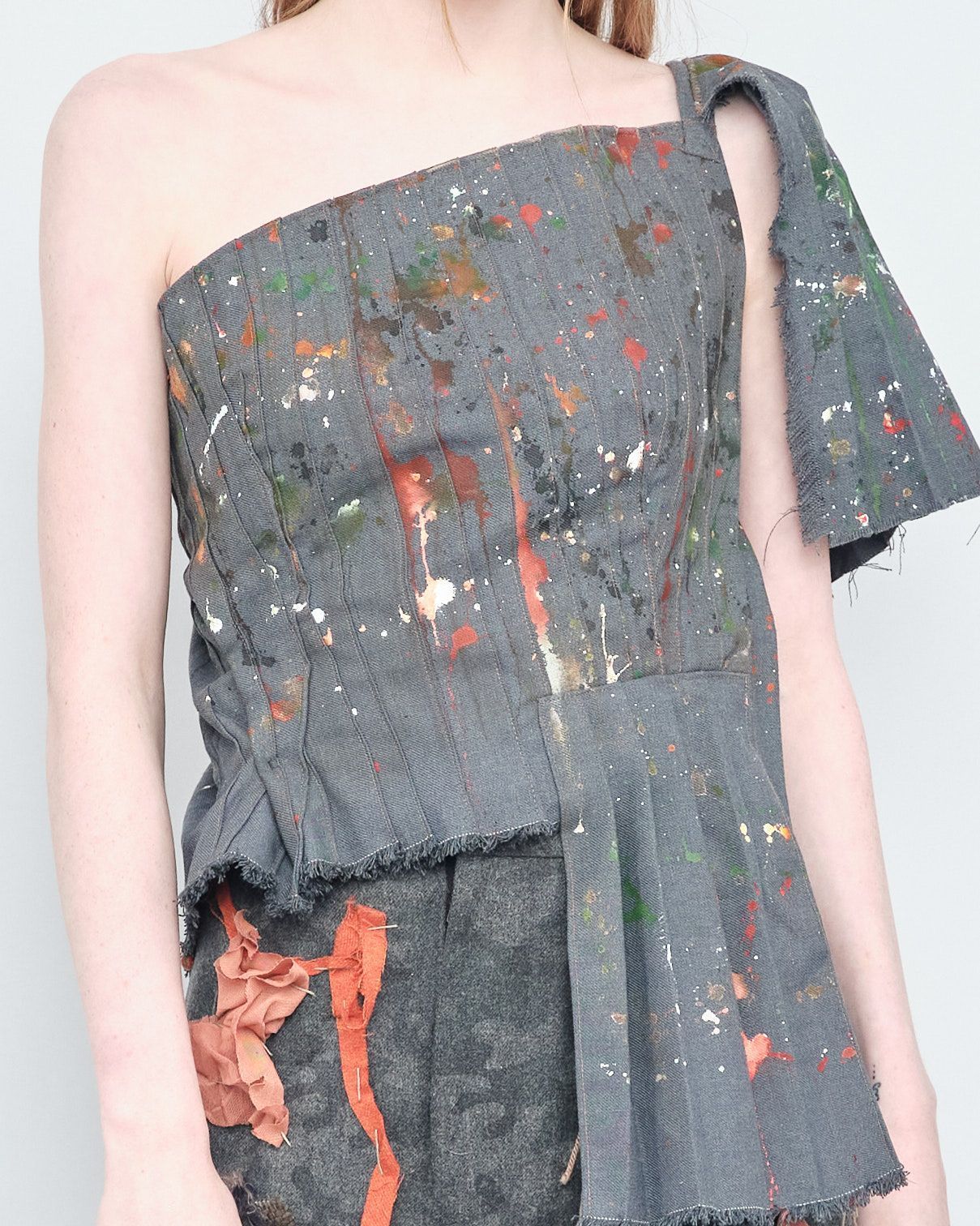 A woman is wearing a gray one shoulder top