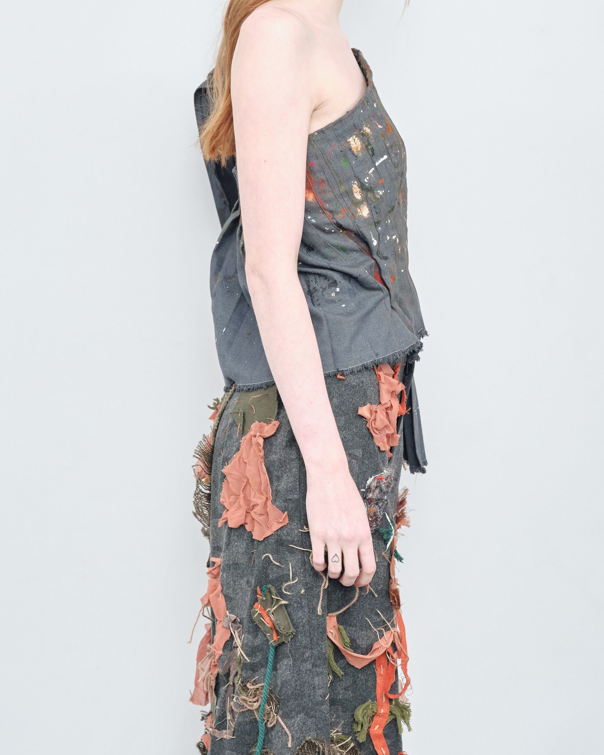 A woman is wearing a gray one shoulder top and pants.