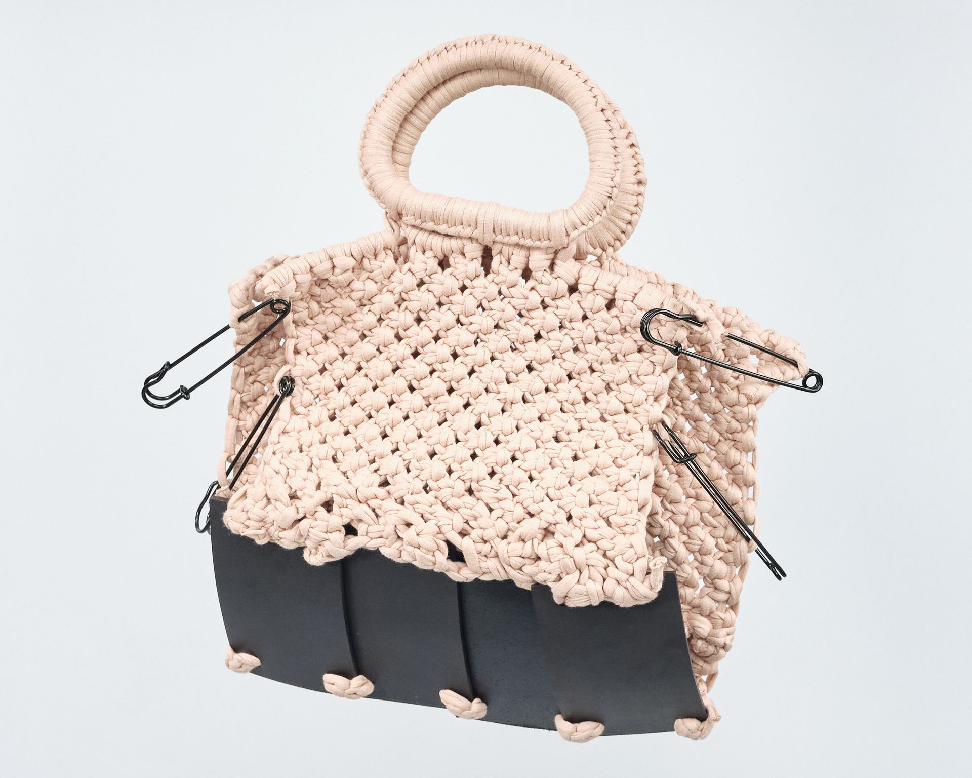 A crocheted bag with a safety pin on the side.