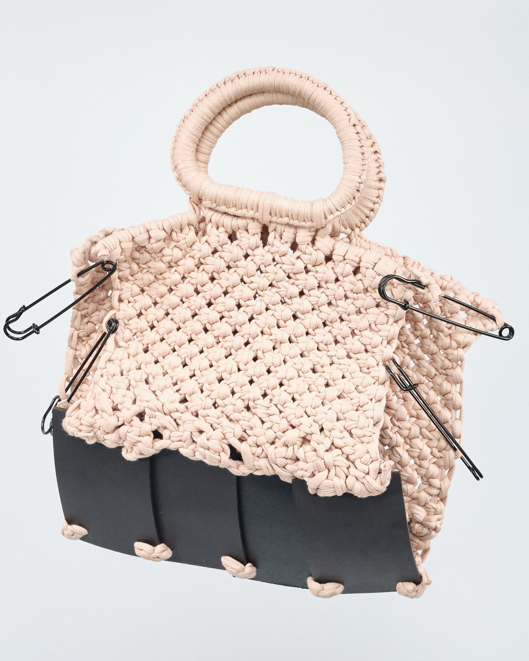A crocheted bag with a safety pin on the side.