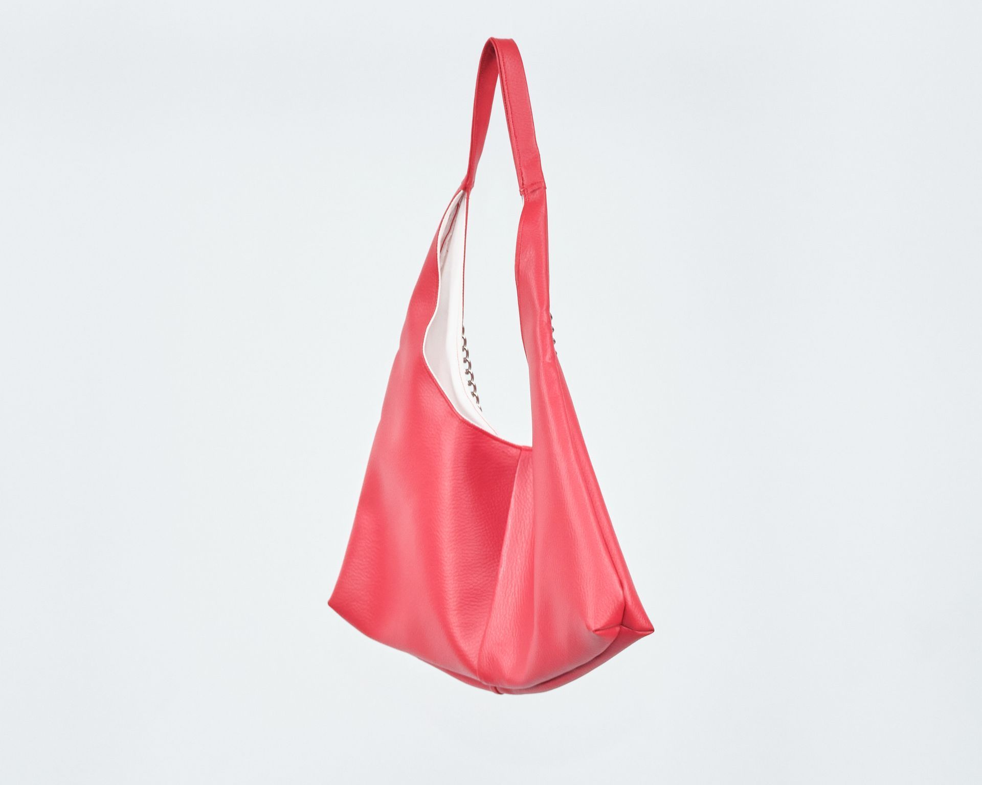 A pink bag with a long handle is hanging on a white background.