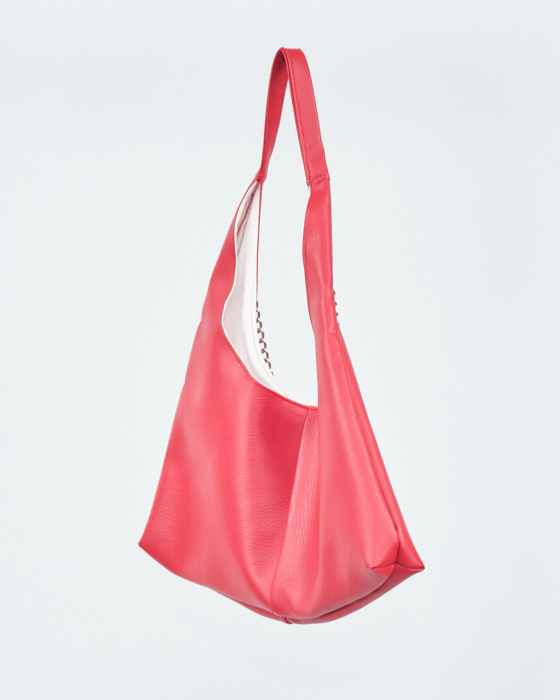 A red bag with a white lining and a red handle is sitting on a white surface.