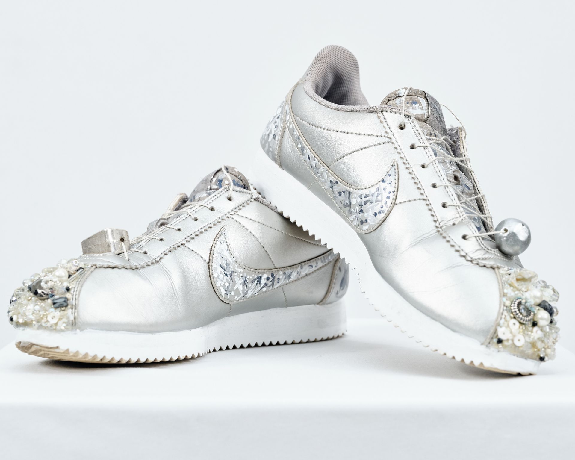 A pair of silver and white nike sneakers on a white surface