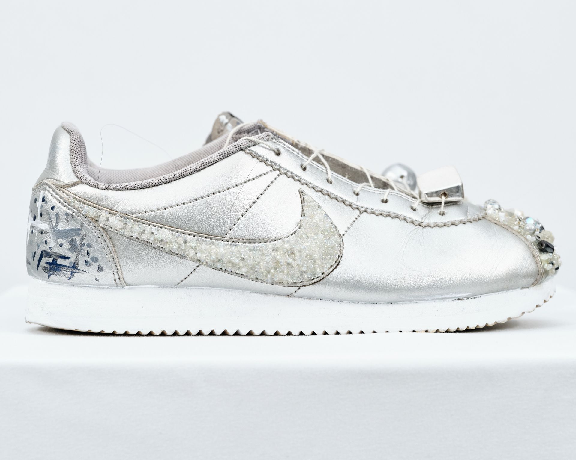 A pair of silver and white nike sneakers on a white surface