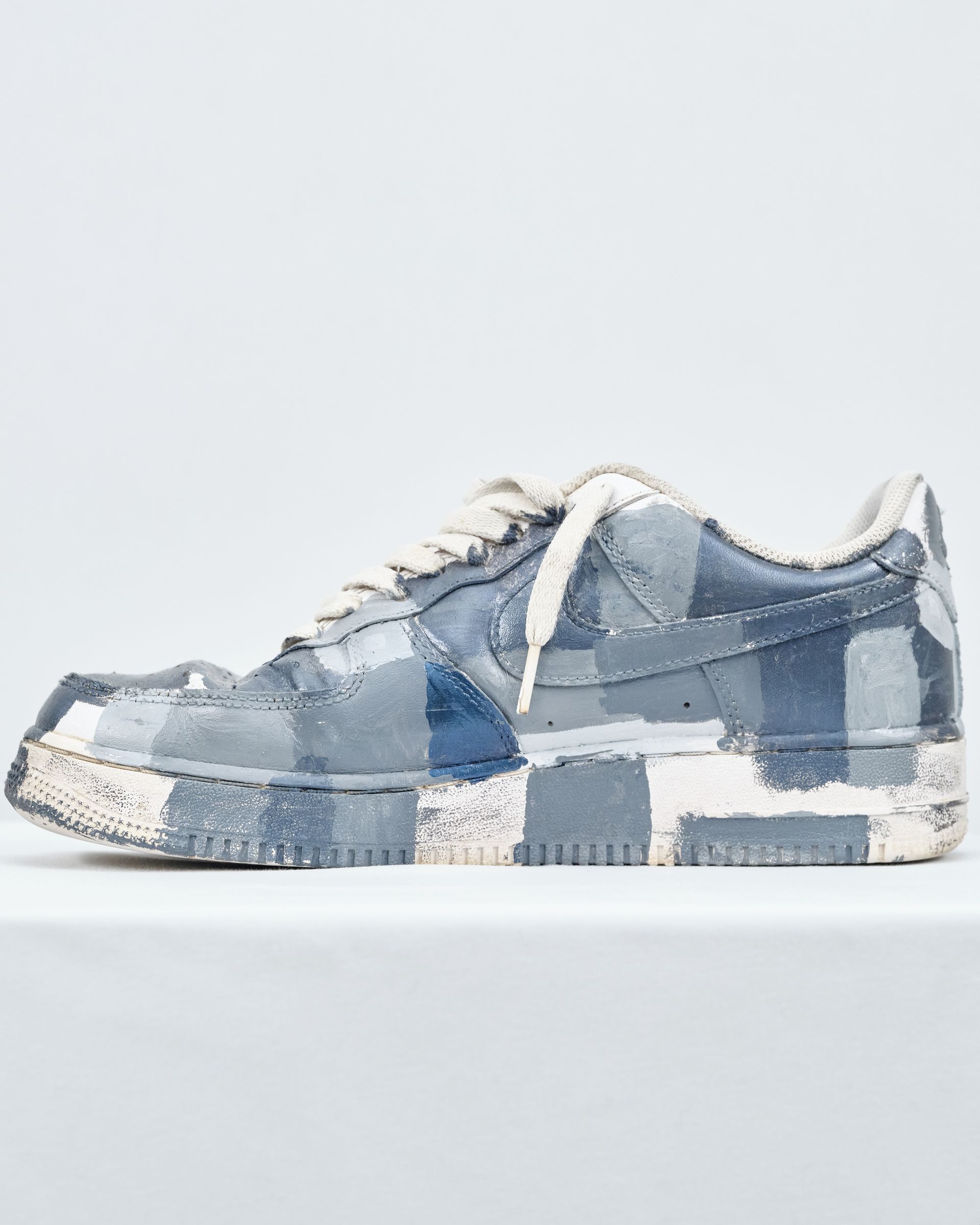 A pair of blue and white sneakers on a white surface.