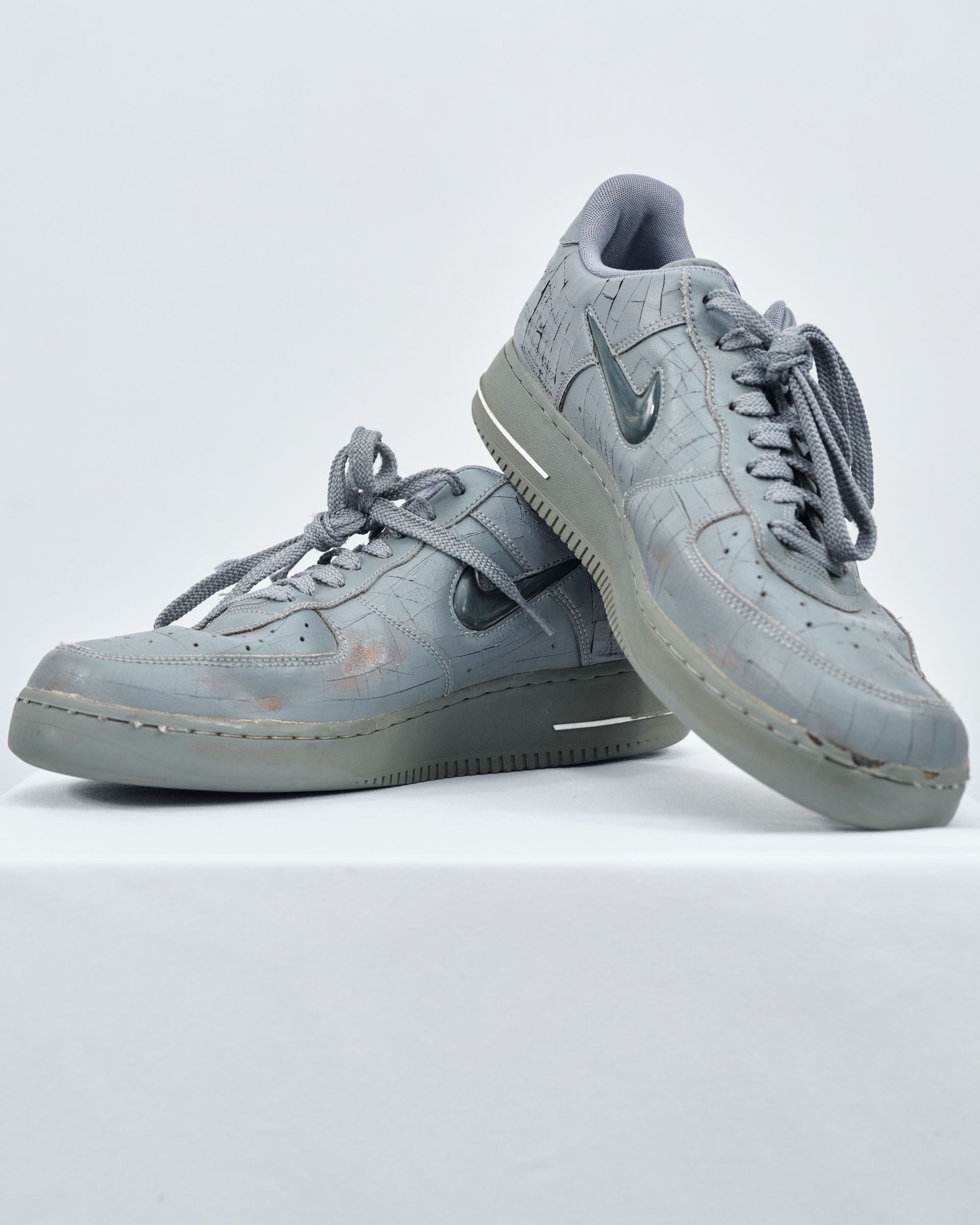 A pair of grey nike air force 1 sneakers on a white surface