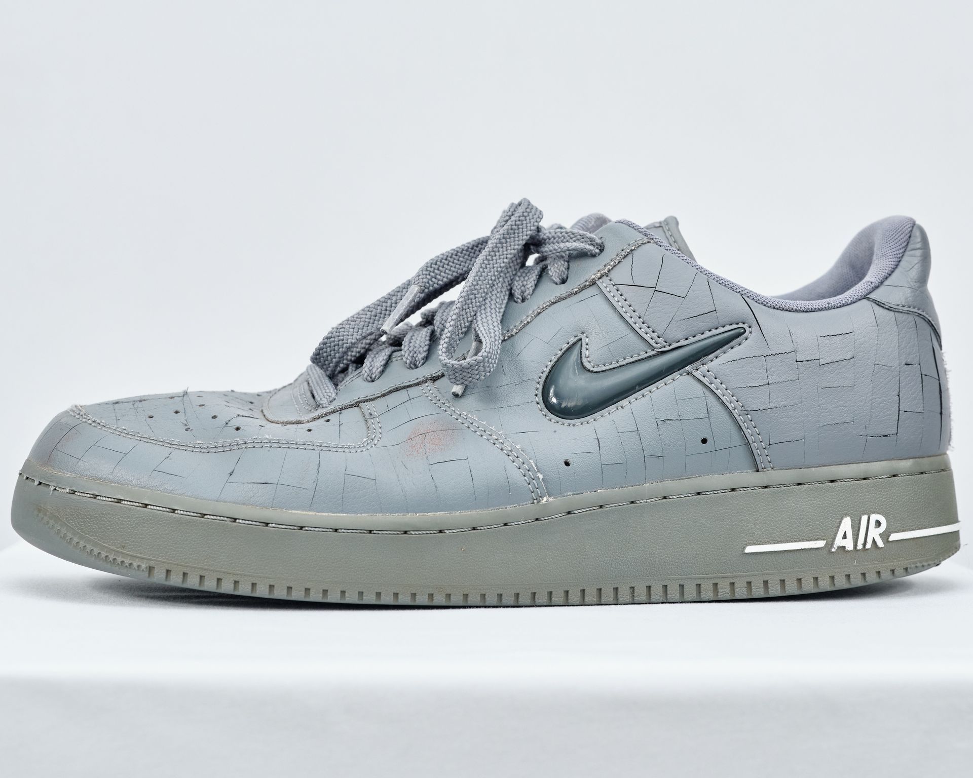 A pair of grey nike air force 1 sneakers on a white surface