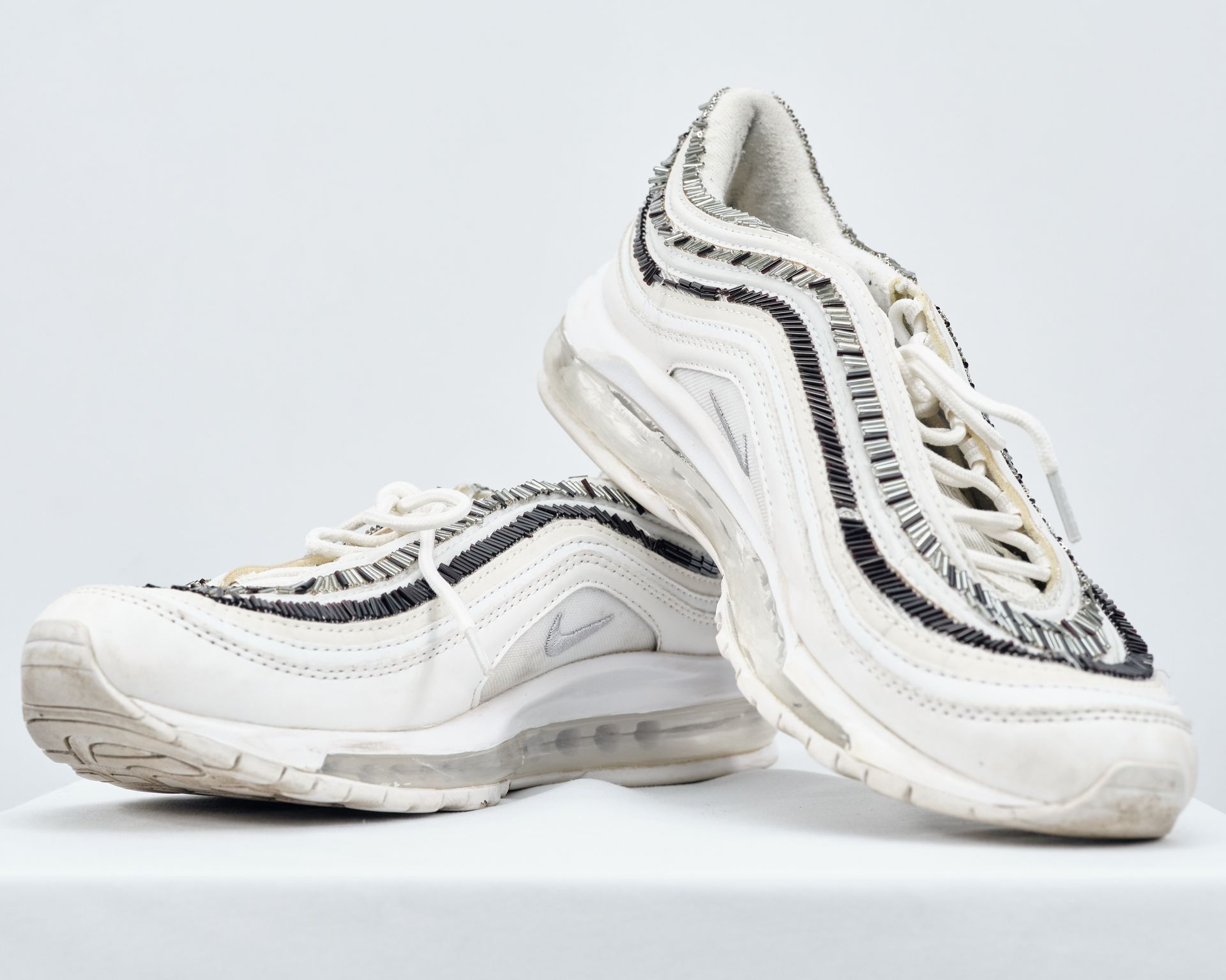 A pair of white nike air max 97 sneakers on a white surface.