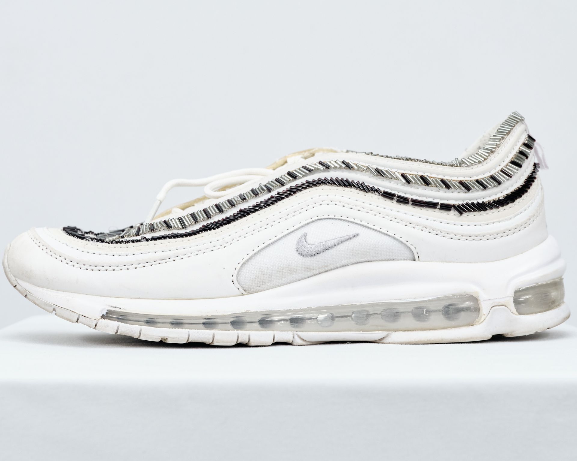 A pair of white nike air max 97 sneakers on a white surface.