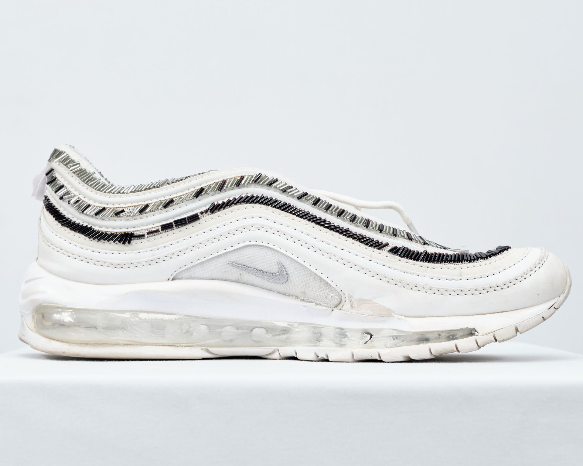 A pair of white nike air max 97 sneakers on a white surface.