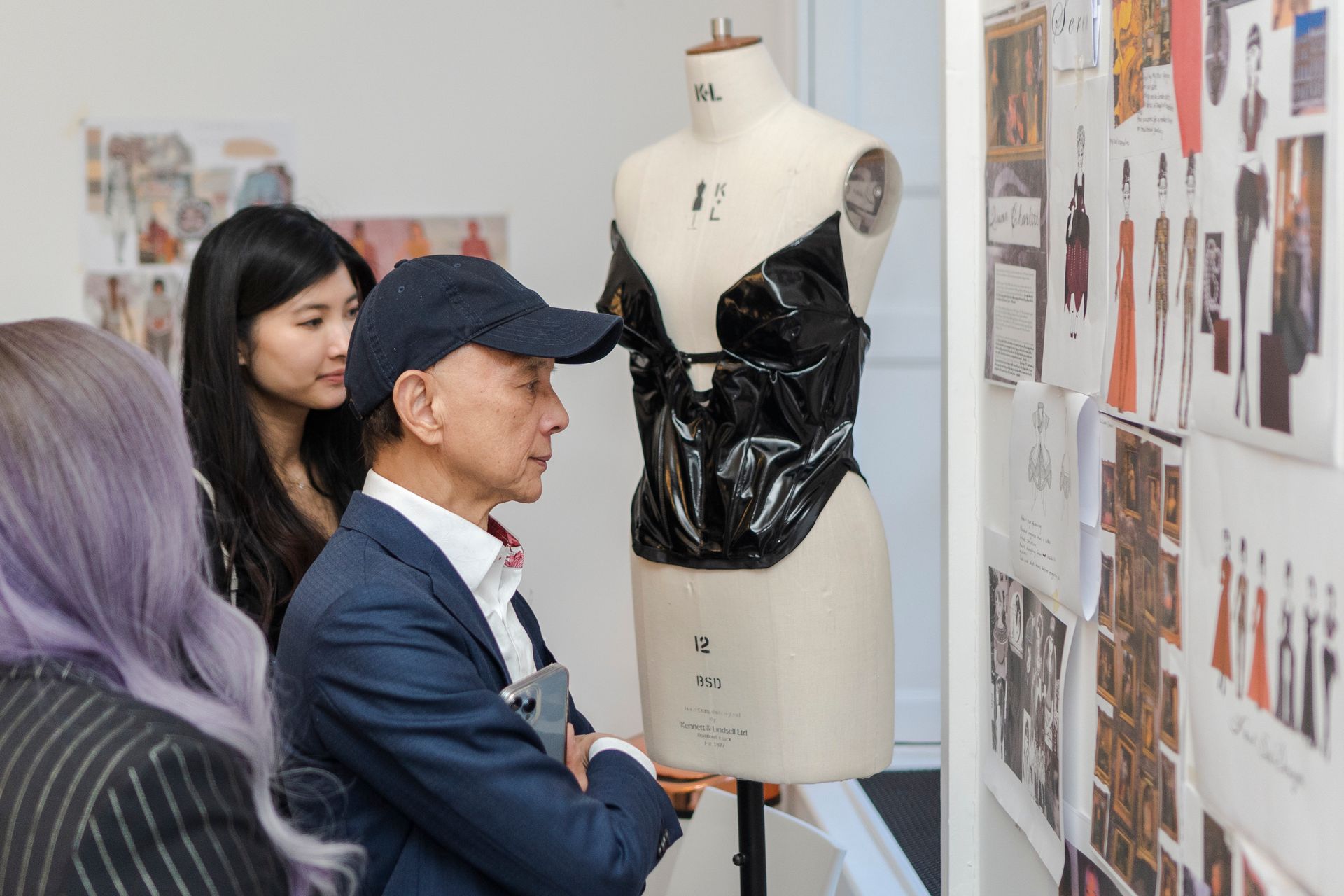 Man in suit seated, smiling in front of large window. Sunlight streams through the glass.