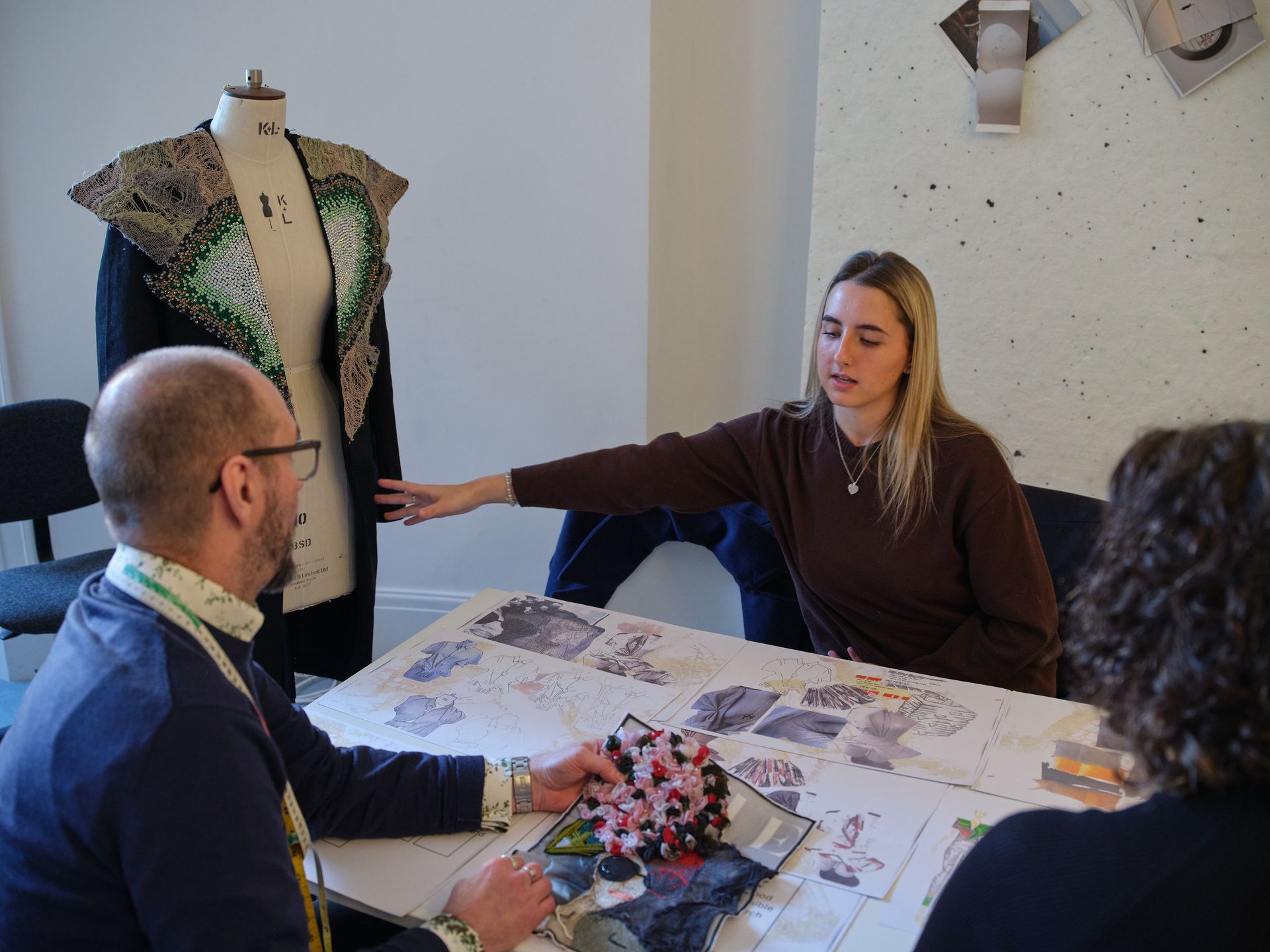 Man in suit seated, smiling in front of large window. Sunlight streams through the glass.