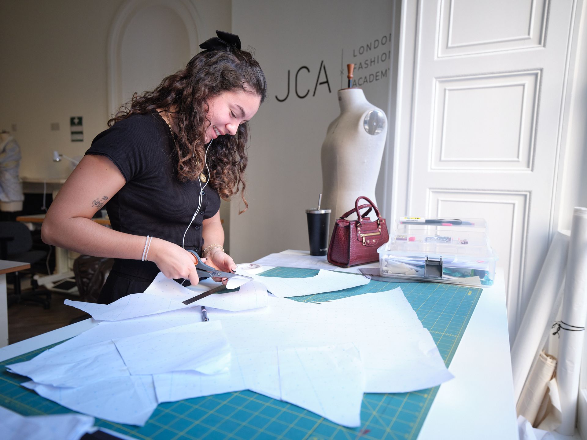 Man in suit seated, smiling in front of large window. Sunlight streams through the glass.