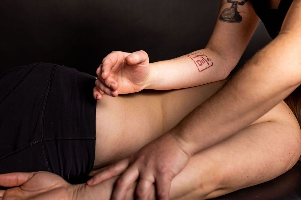 Hands pressing on a person’s bare torso during a massage, with black shorts visible