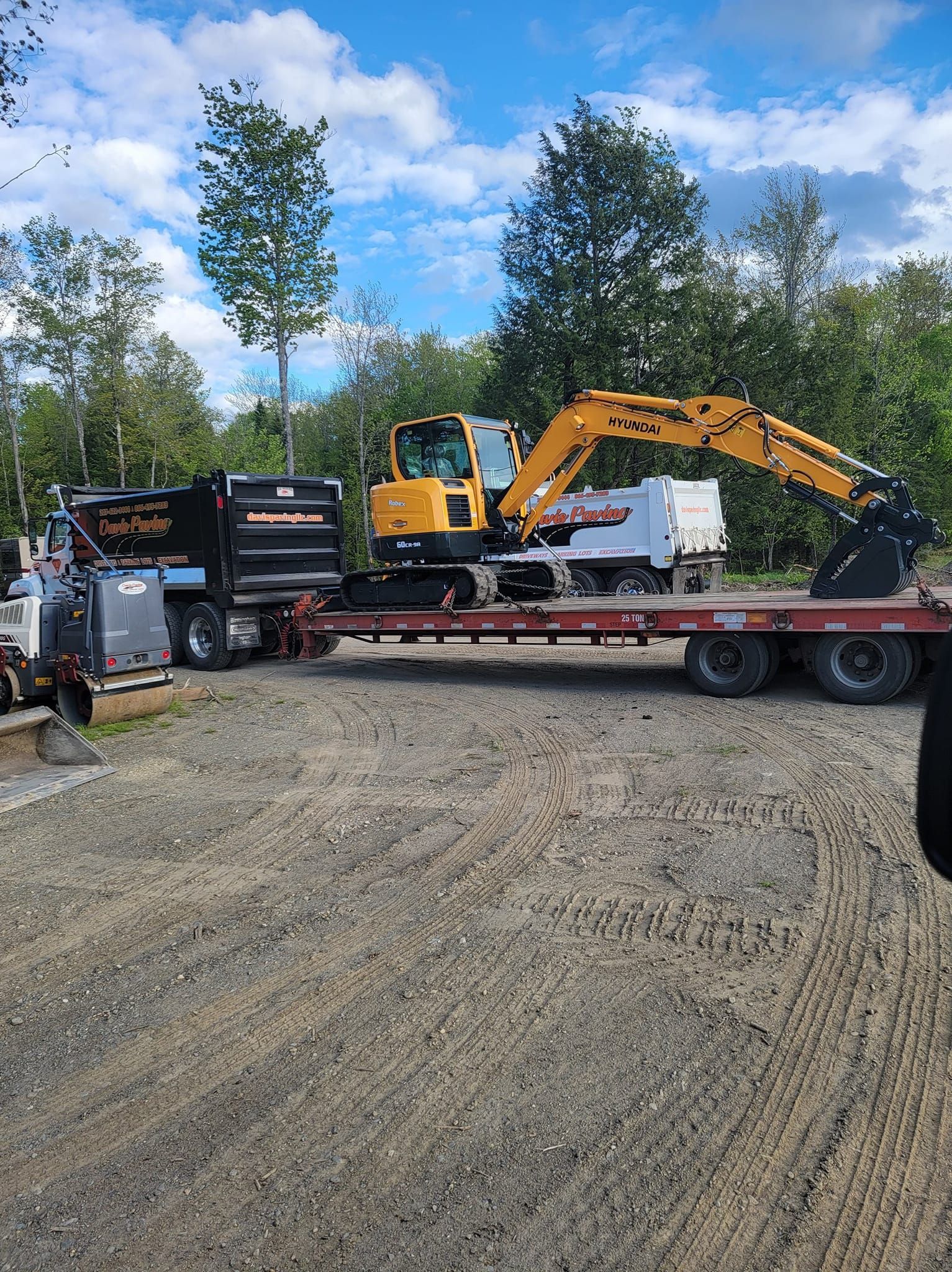 Residential building with freshly sealed asphalt driveway; orange cone near sewer.
