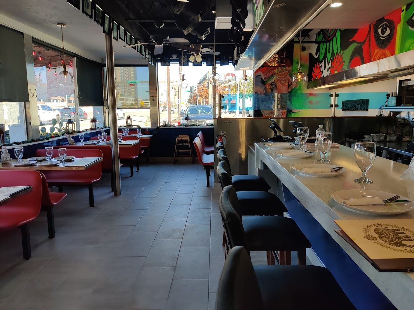 Restaurant interior with red booths, a bar with stools, and colorful murals.