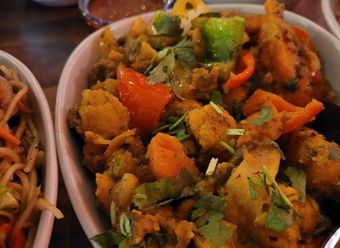 Close-up of a dish with fried vegetables and peppers garnished with cilantro in a white bowl.