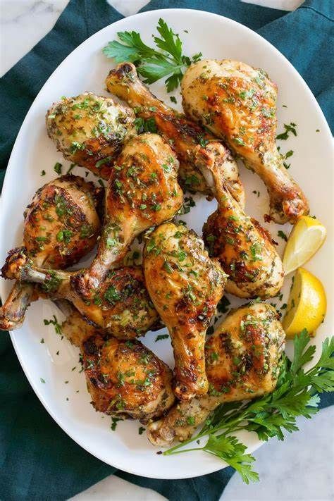 Roasted chicken drumsticks on a white platter garnished with parsley and lemon.
