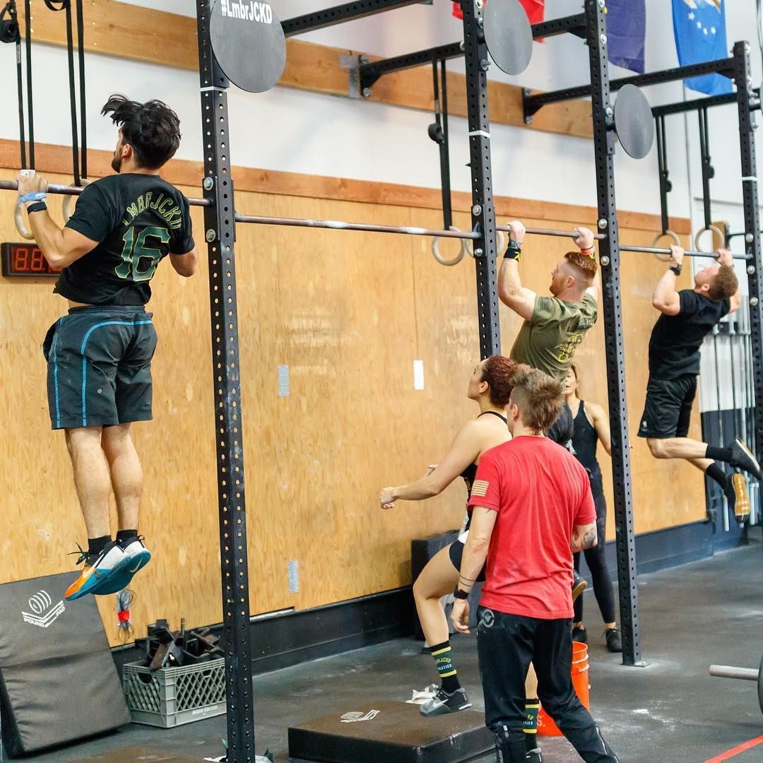 A group of people are doing pull ups in a gym