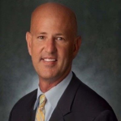A bald man in a suit and tie smiles for the camera