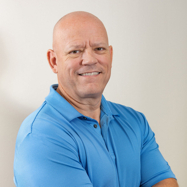 A man in a suit and tie is standing in front of a white background.
